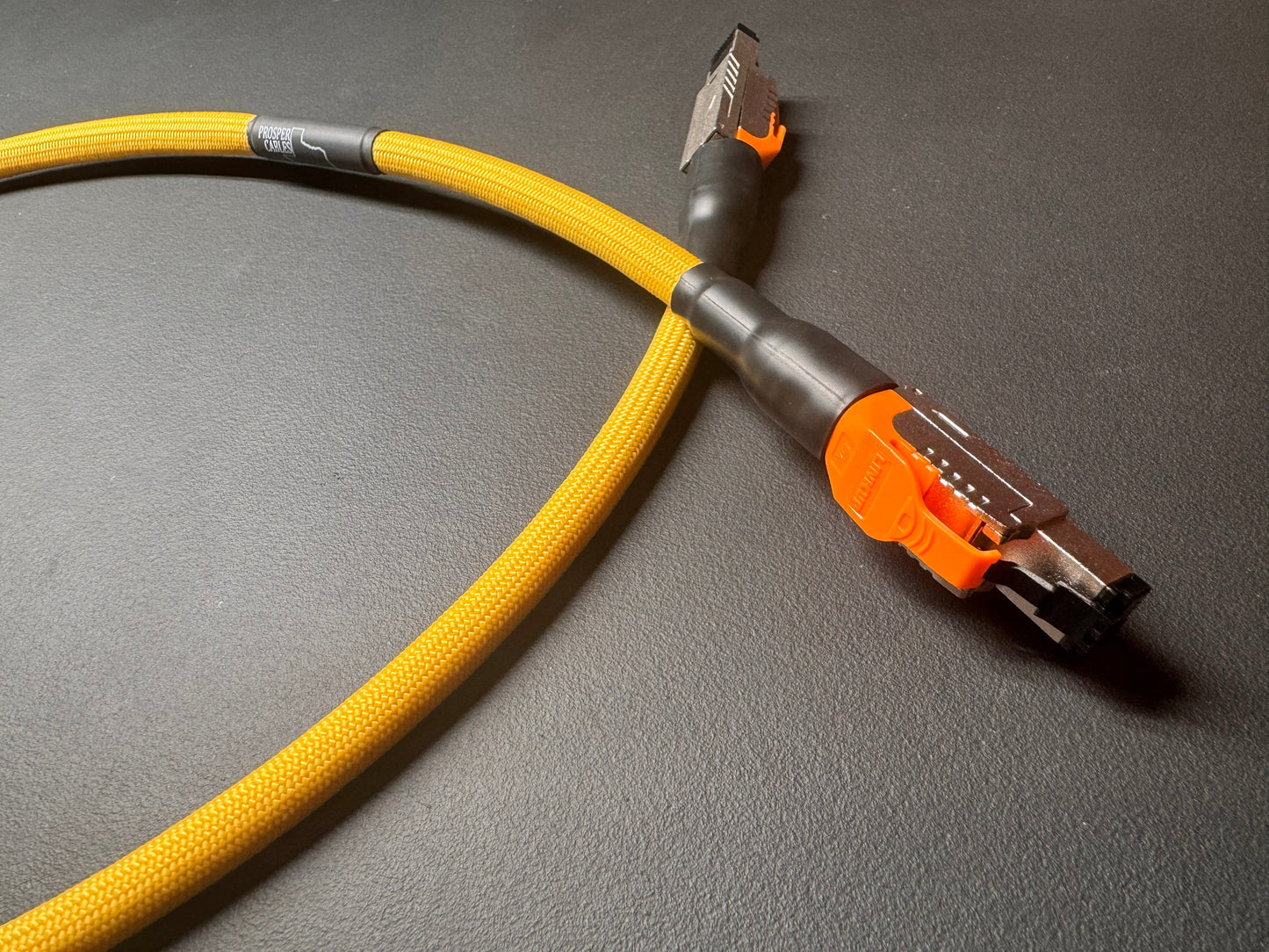 a yellow cable with an orange connector lying on a gray surface.