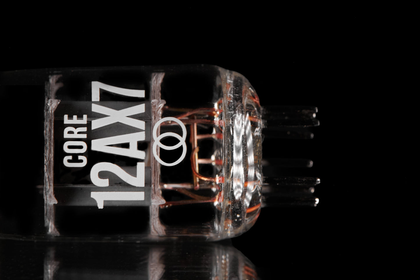 A close-up studio shot of a transparent glass vacuum tube labeled 'CORE 12AX7' with copper-colored internal filaments, set against a solid black background with a subtle reflection below.