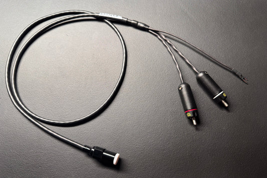 A black audio adapter cable with a 3.5mm plug on one end and two 2-pin connectors on the other, displayed on a dark textured surface.