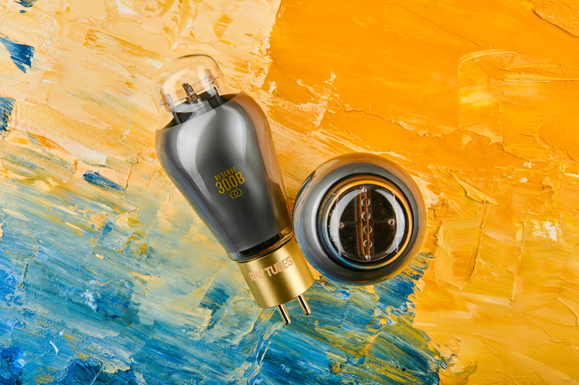 A RESERVE 300B vacuum tube with a black glass body and gold base, shown alongside its metal base cap on a textured, colorful background of yellow, orange, and blue paint strokes.