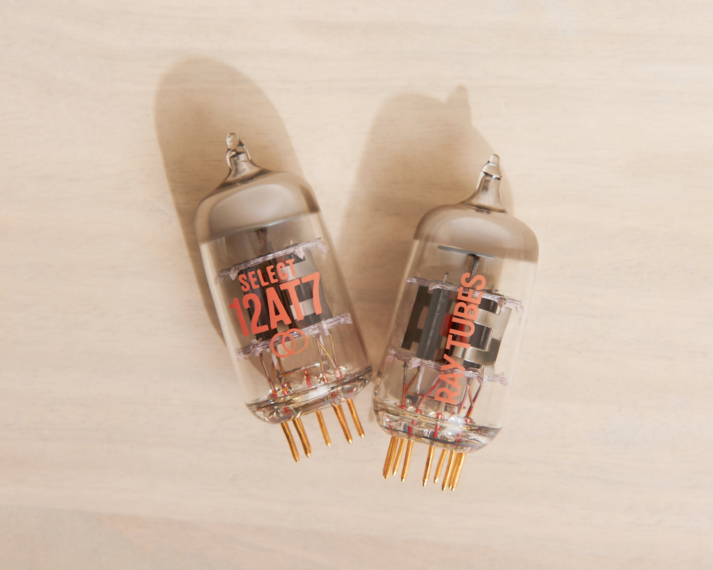Two vacuum tubes with visible branding on a beige background