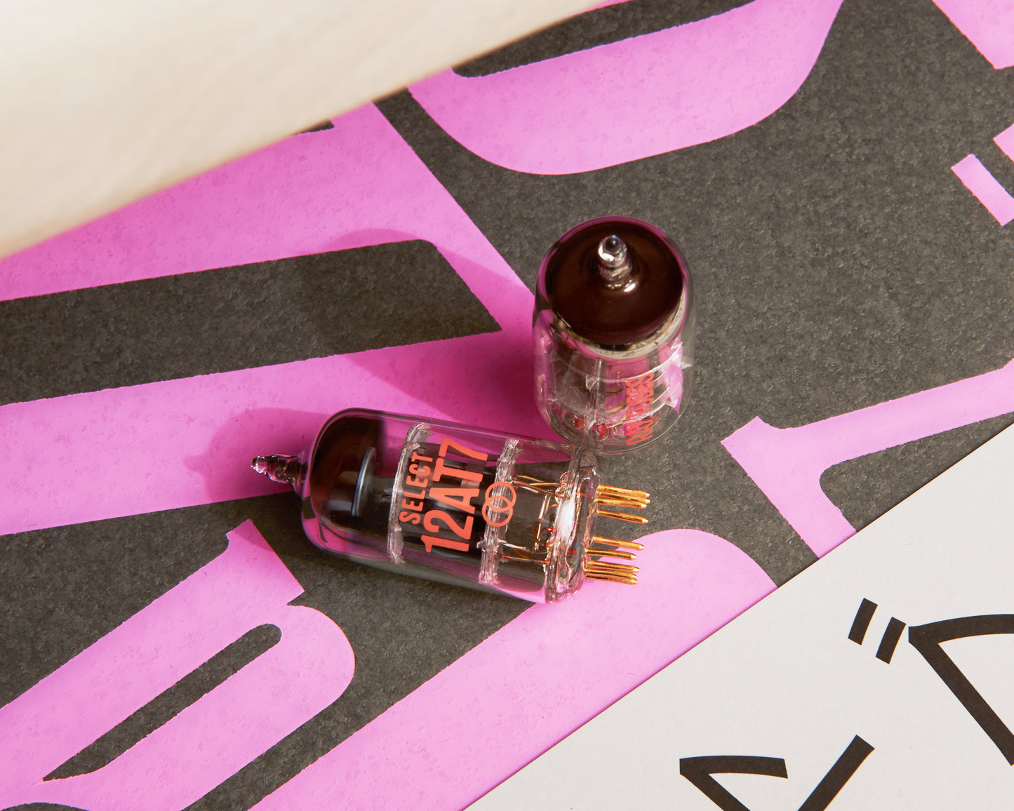 Two vacuum tubes on a pink and black background with text