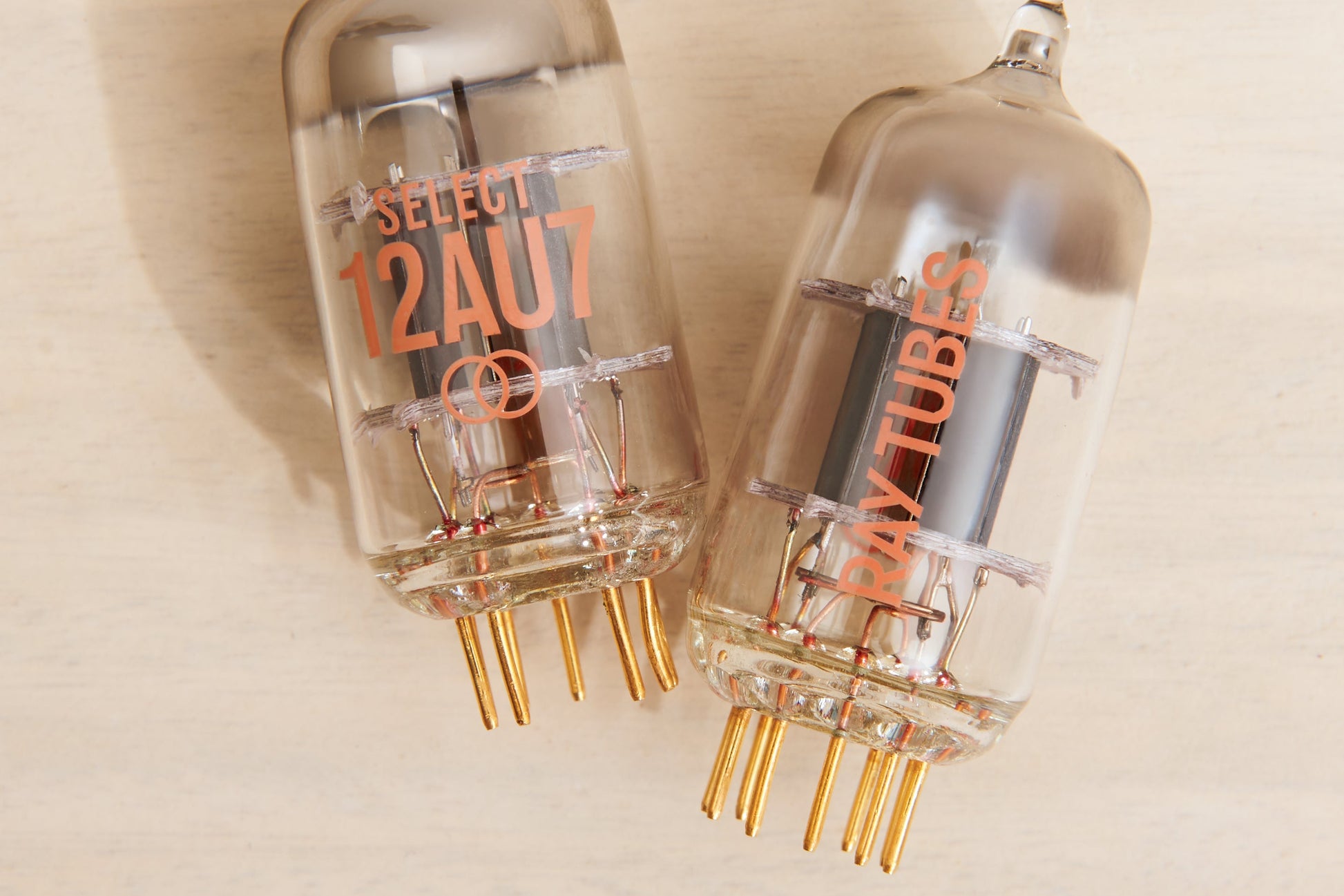 Two vacuum tubes with '12AU7' and 'RAY TUBES' branding on a beige background