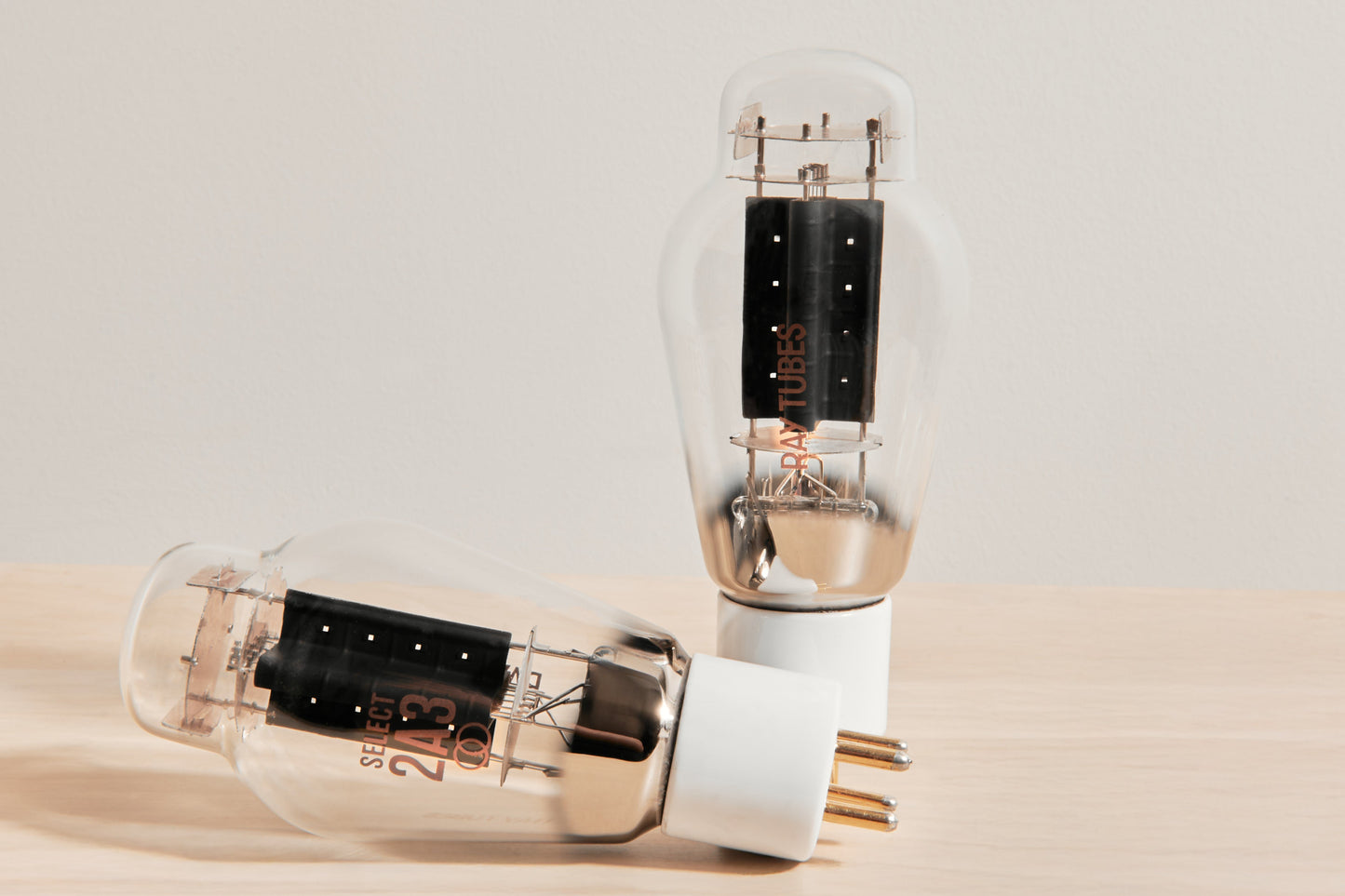 Two vacuum tubes on a beige surface with a light gray background