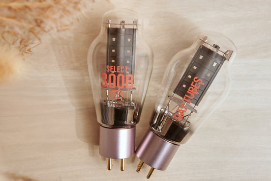 Two vacuum tubes with metallic bases on a textured beige background