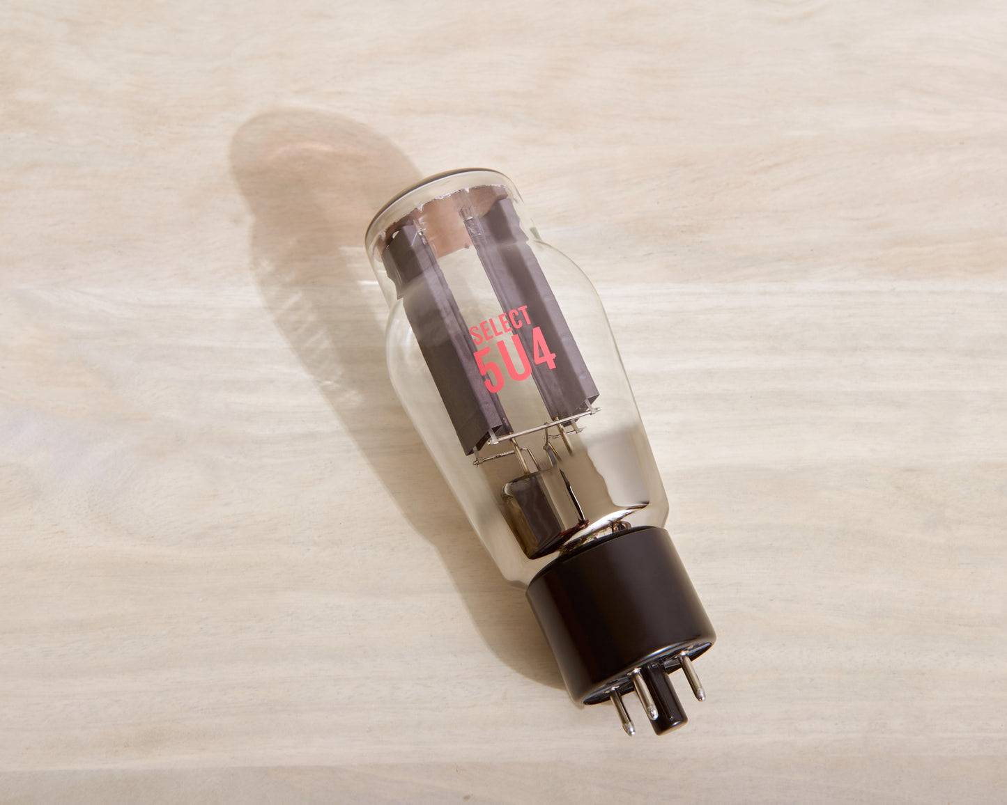 A glass vacuum tube with a black base, featuring red printed text reading 'SELECT 5U4' on the clear glass body, photographed diagonally on a light wood grain surface.