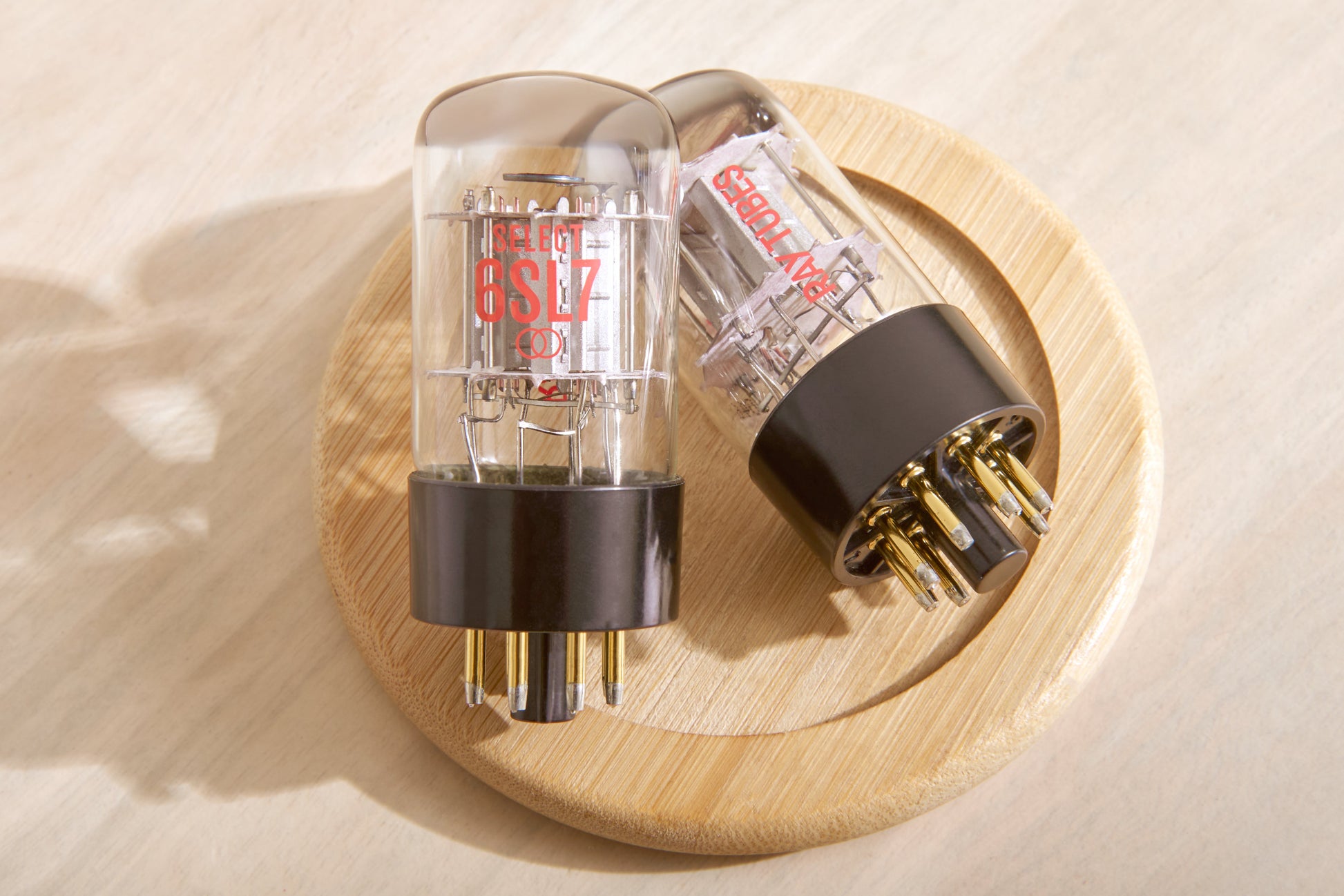 Two vacuum tubes on a wooden surface with a neutral background