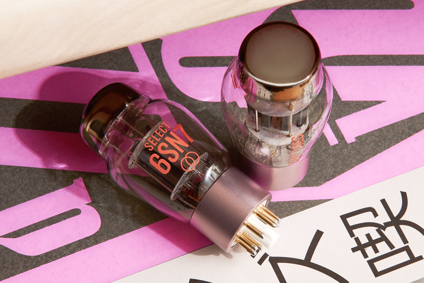 Two vacuum tubes on a pink and black patterned surface