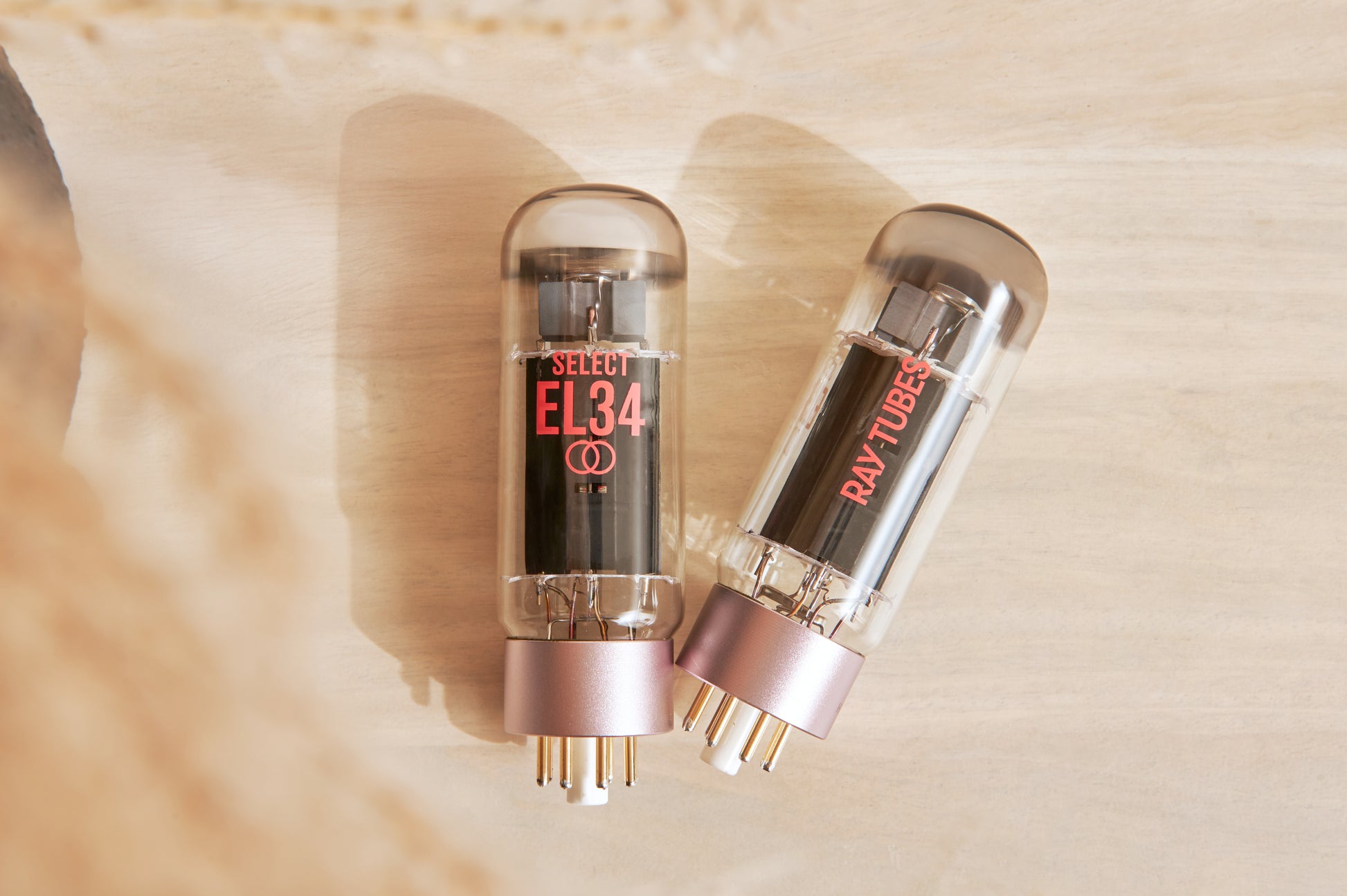 Two vacuum tubes with 'EL34' marking on a beige background