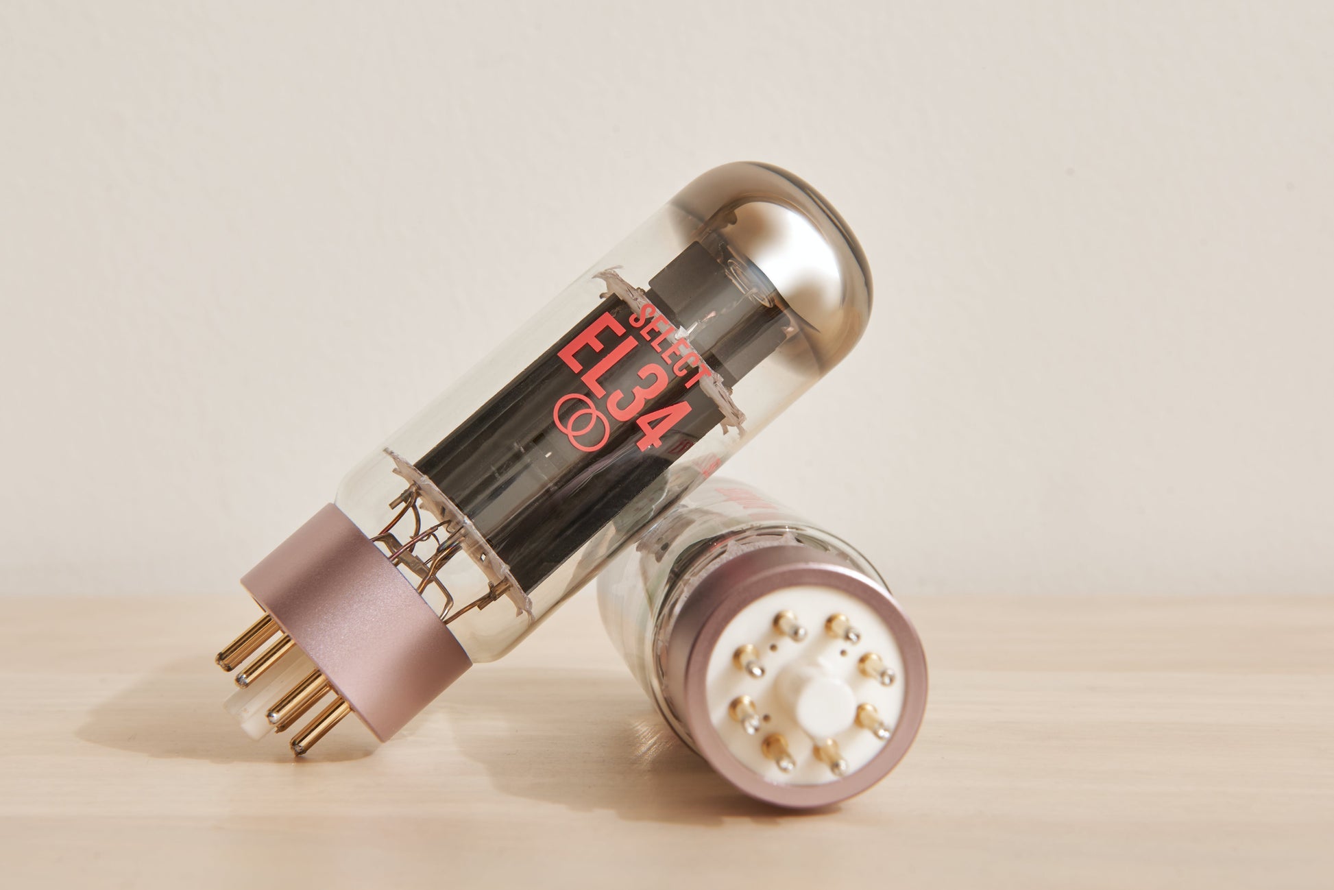 Two vacuum tubes with 'EL34' marking on a beige background