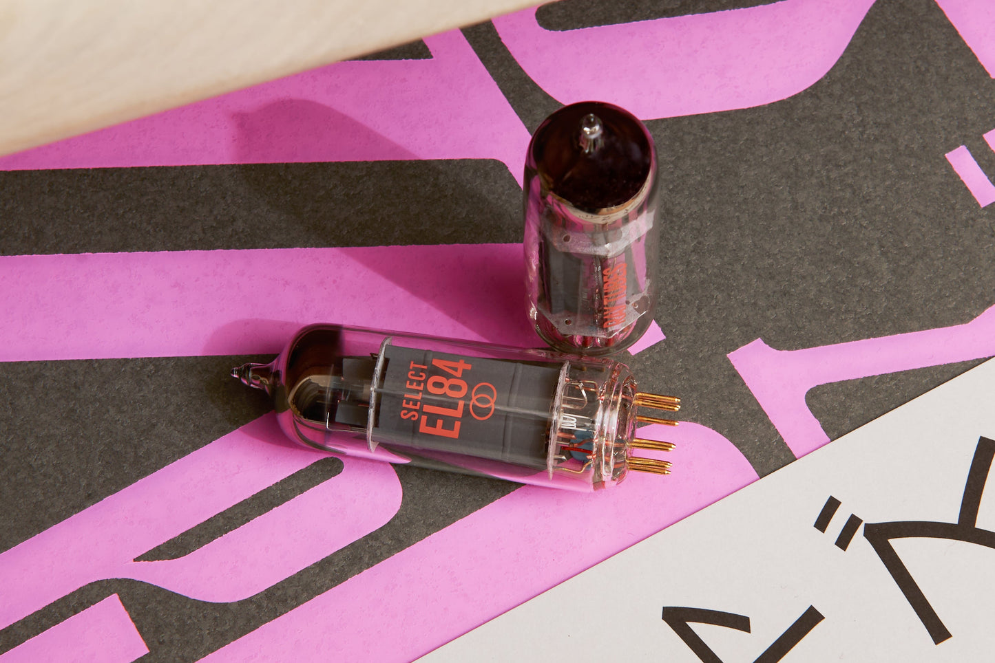 Two vacuum tubes on a pink and black patterned surface